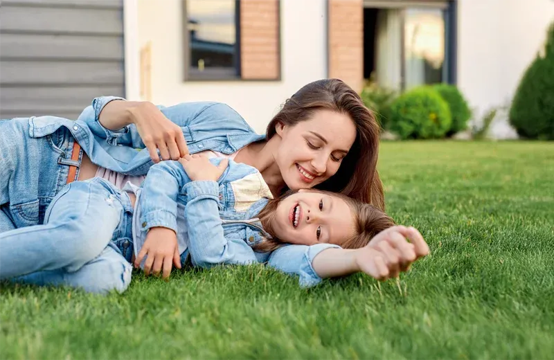 mother and daughter laying in green healthy grass