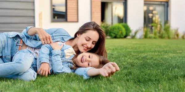 mother and daughter laying in green healthy grass